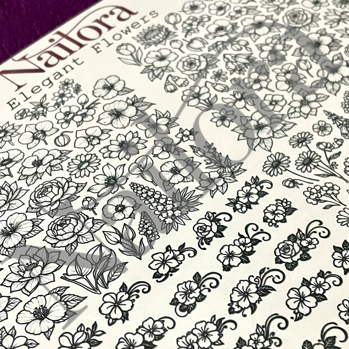 A close-up of a nail art D|IY decal sheet featuring black floral line-art designs on an off-white background. The brand name 'Nailora' is visible in the top left corner, along with the text 'Elegant Flowers'.