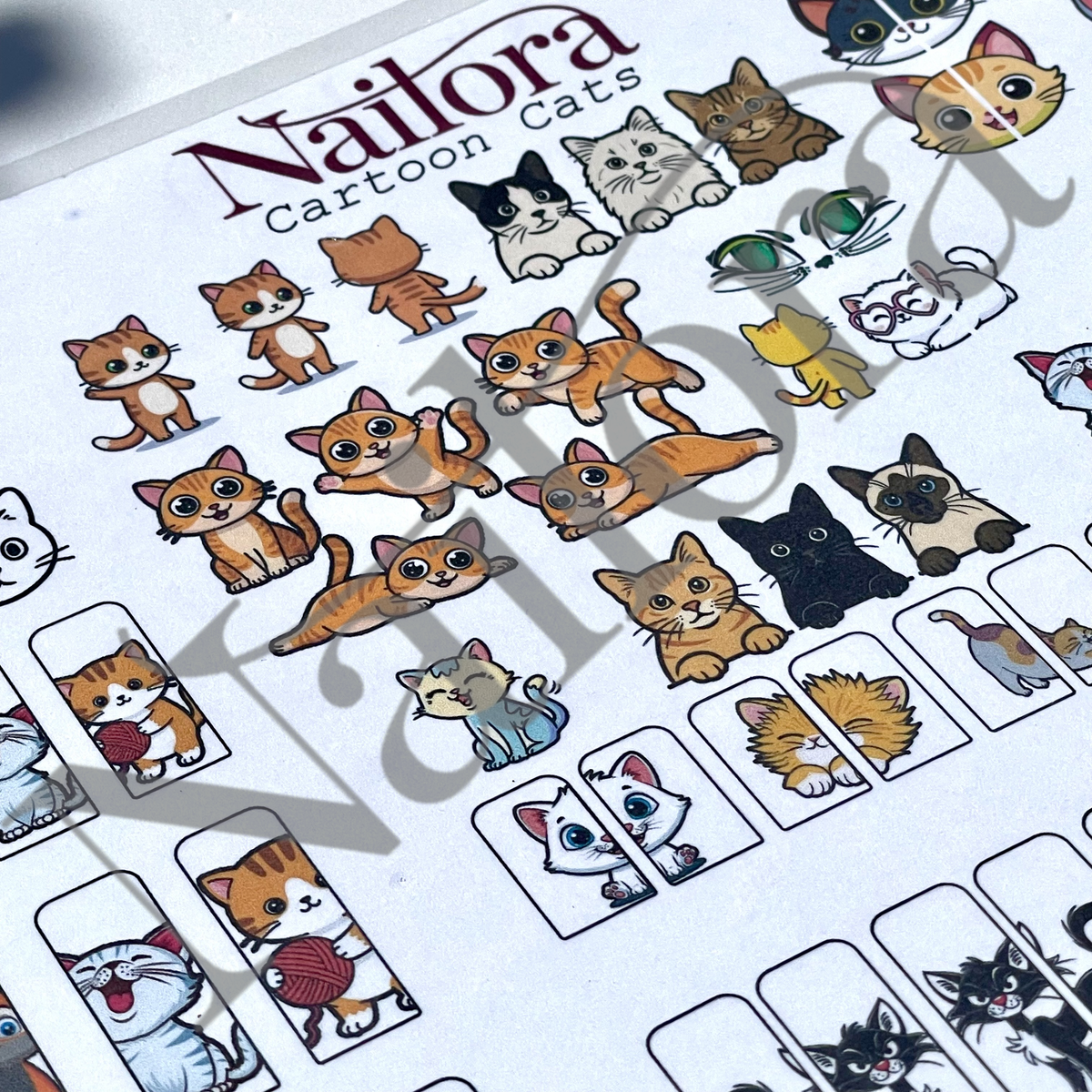 A close-up of a make your own nail art sticker sheet featuring various cartoon cat illustrations. The sheet has the brand name 'Nailora' printed at the top, with multiple cartoon cat designs in orange, black, white, and other colors, along with small rectangular boxes showing additional cat face and body sticker options.
