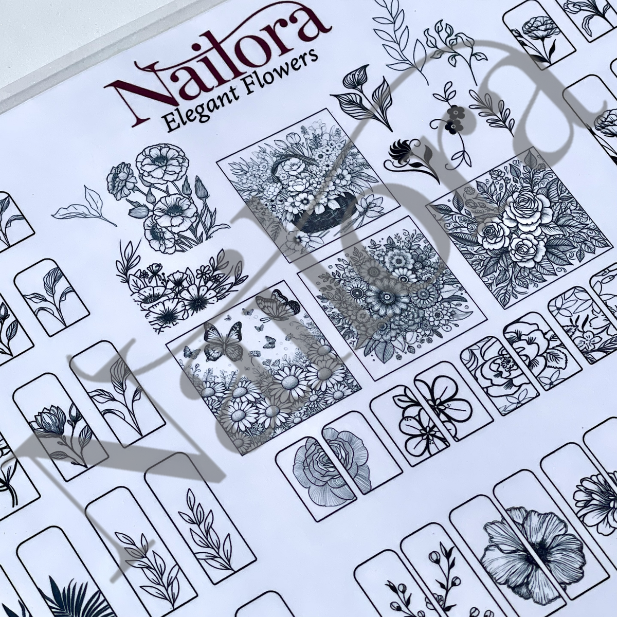 A sheet of nail art designs, simply trace to make your own nail art decals  featuring intricate black and white floral designs, with the brand name 'Nailora' printed at the top.