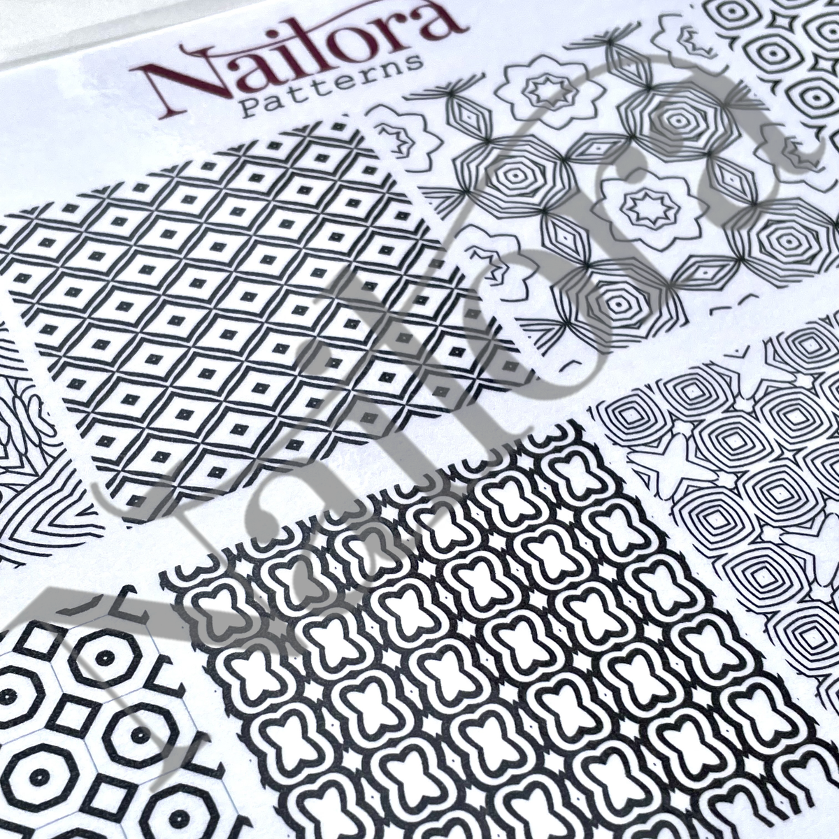 A close-up of Nailora Patterns nail nail art sheets showing various black and white geometric and floral designs.