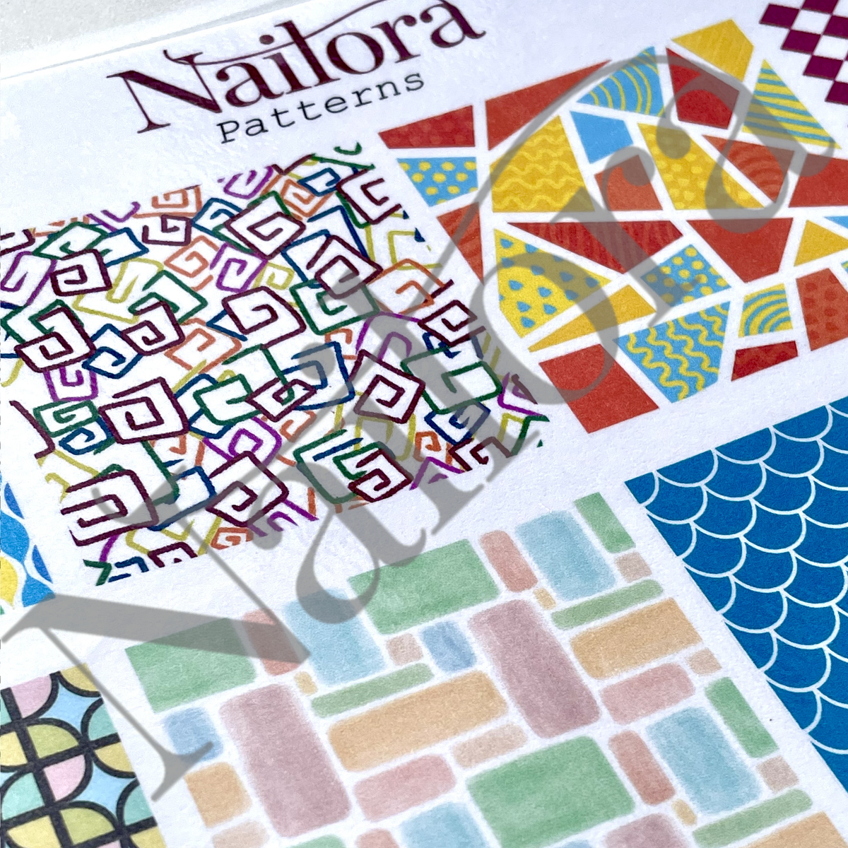 A close-up of a Nailora Patterns sheet showing multiple colorful geometric and abstract designs, including lines, mosaics, and watercolor-style blocks on a white background.