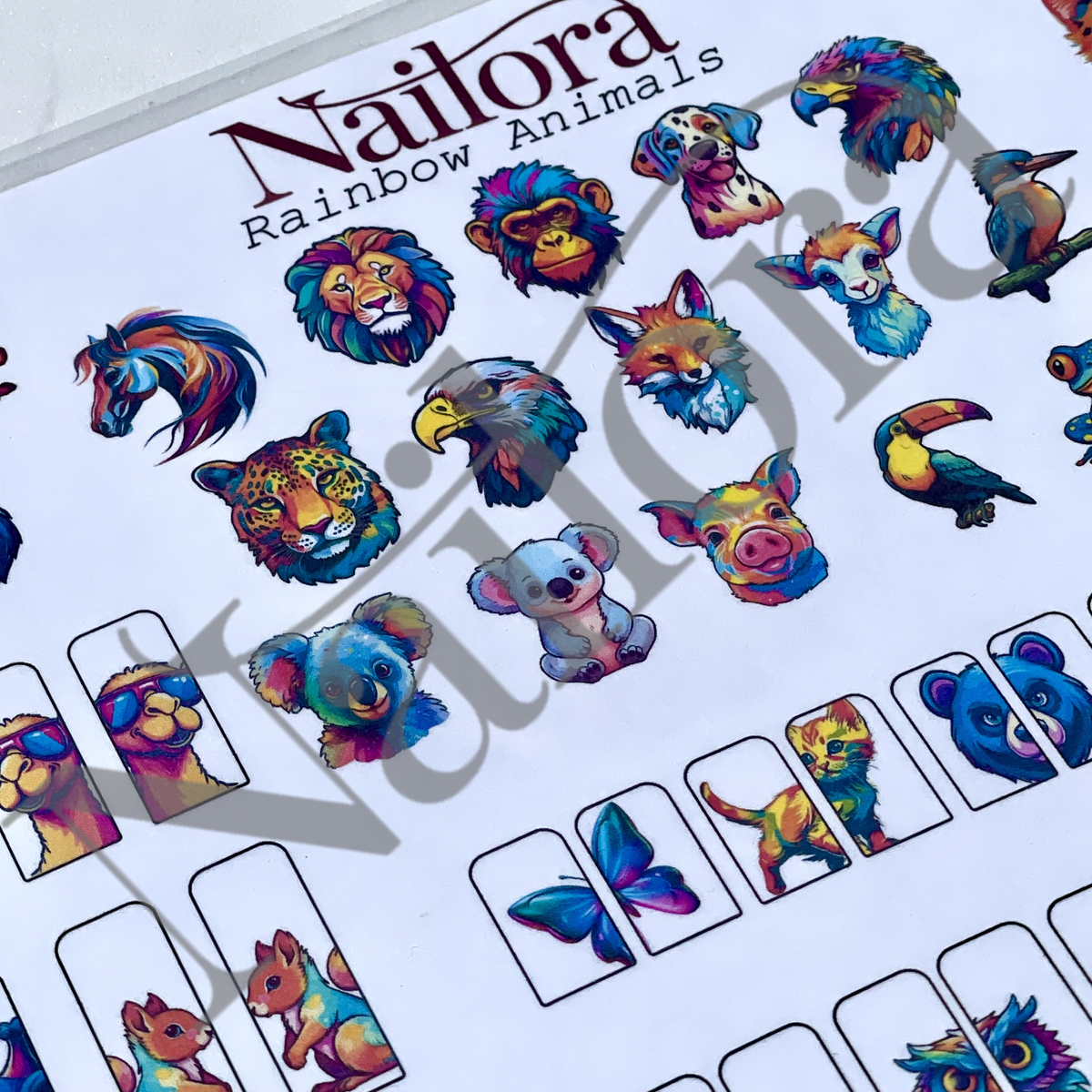 A DIY nail art sheet from the brand Nailora,  trace the design using gel polish and peel off, featuring colorful rainbow animal illustrations such as lions, monkeys, foxes, toucans, koalas, and butterflies, alongside small rectangular sample boxes showing how the stickers look applied to a nail.
