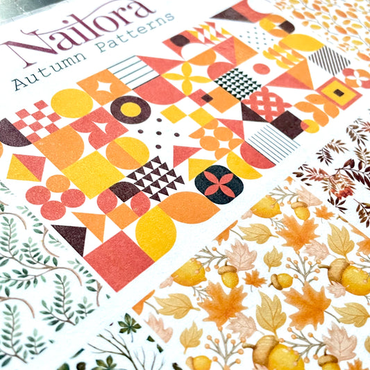 A close-up of a Nailora Autumn Patterns sheet featuring a colorful geometric design in orange, yellow, red, and brown, with another patterned sheet showing autumn leaves and acorns.